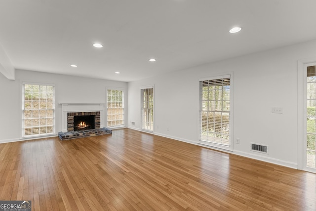 unfurnished living room with light wood-style flooring, a brick fireplace, visible vents, and recessed lighting