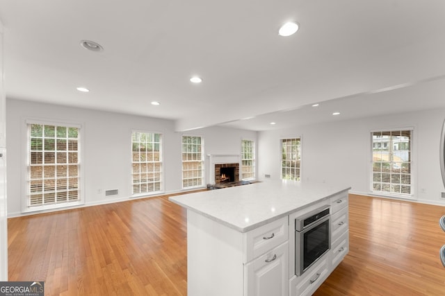 kitchen featuring a center island, light countertops, open floor plan, visible vents, and white cabinets