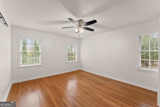 empty room featuring a barn door, a healthy amount of sunlight, and wood finished floors