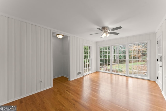 empty room with ceiling fan, ornamental molding, visible vents, and light wood-type flooring