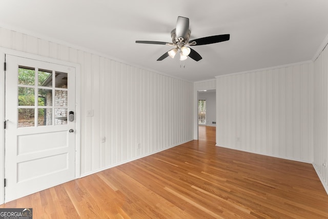 empty room featuring crown molding, a ceiling fan, wood finished floors, and plenty of natural light