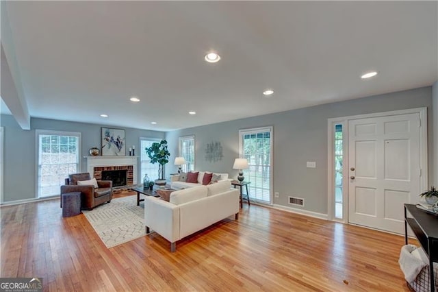 living room with baseboards, visible vents, recessed lighting, a fireplace, and light wood finished floors