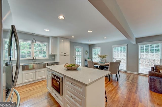 kitchen with stainless steel appliances, a center island, hanging light fixtures, and white cabinetry