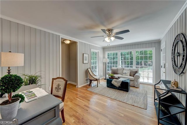 living area with ceiling fan, ornamental molding, light wood-style floors, and plenty of natural light