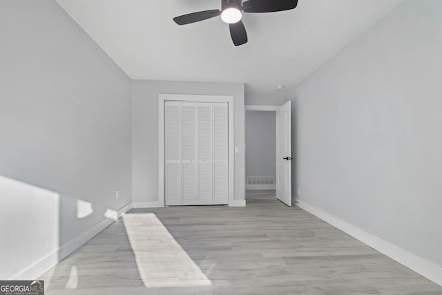 unfurnished bedroom featuring ceiling fan, a closet, and light wood-type flooring