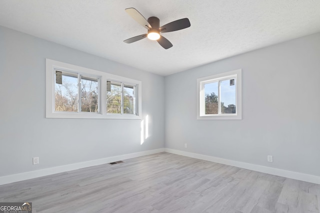 empty room with ceiling fan, light hardwood / wood-style flooring, and a textured ceiling