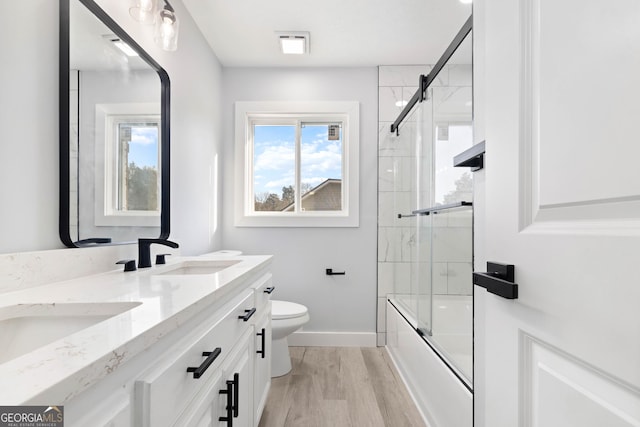 full bathroom with wood-type flooring, toilet, enclosed tub / shower combo, and vanity