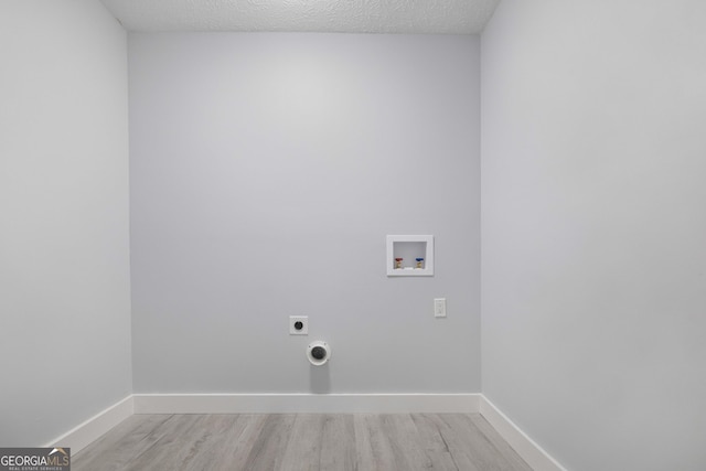 clothes washing area with washer hookup, light hardwood / wood-style flooring, hookup for an electric dryer, and a textured ceiling