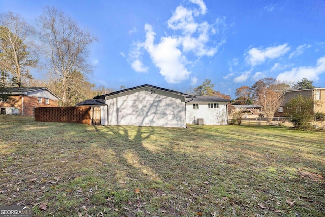 exterior space with central AC unit and a lawn