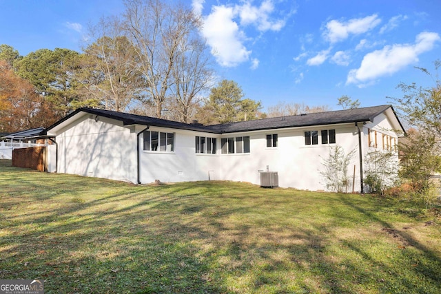 rear view of property featuring a lawn and central AC