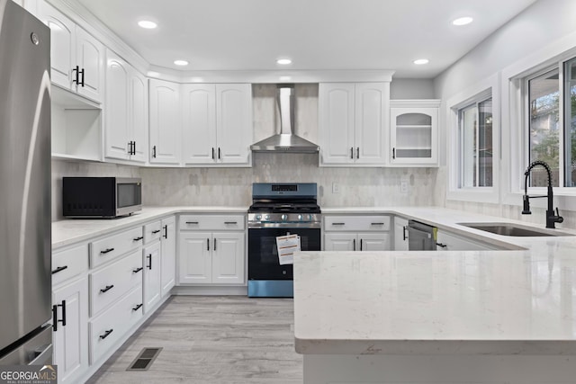 kitchen featuring wall chimney exhaust hood, white cabinets, sink, and appliances with stainless steel finishes