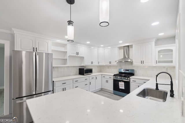 kitchen with appliances with stainless steel finishes, wall chimney exhaust hood, decorative light fixtures, white cabinets, and sink