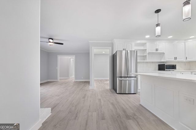 kitchen featuring crown molding, light hardwood / wood-style flooring, pendant lighting, appliances with stainless steel finishes, and white cabinetry