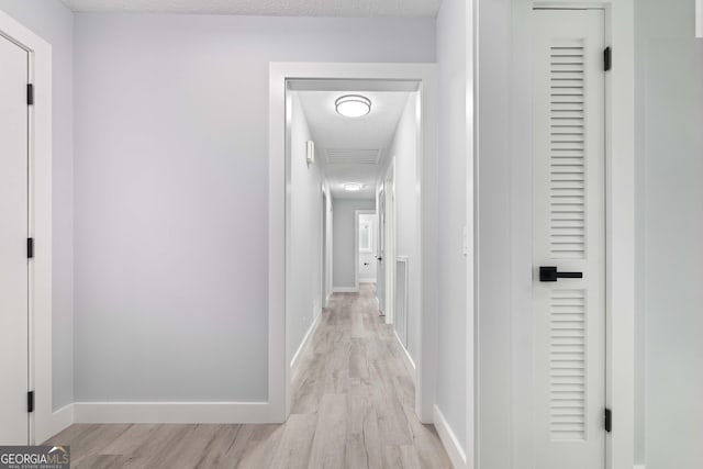 hall featuring light hardwood / wood-style floors and a textured ceiling