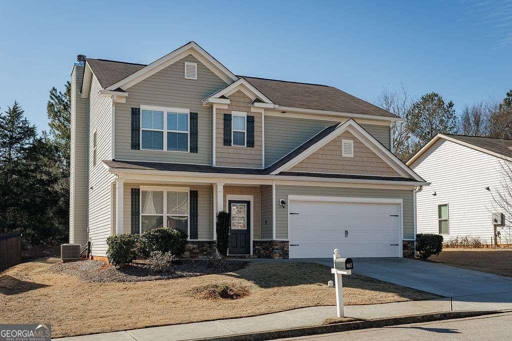 craftsman-style house featuring a garage, cooling unit, and covered porch