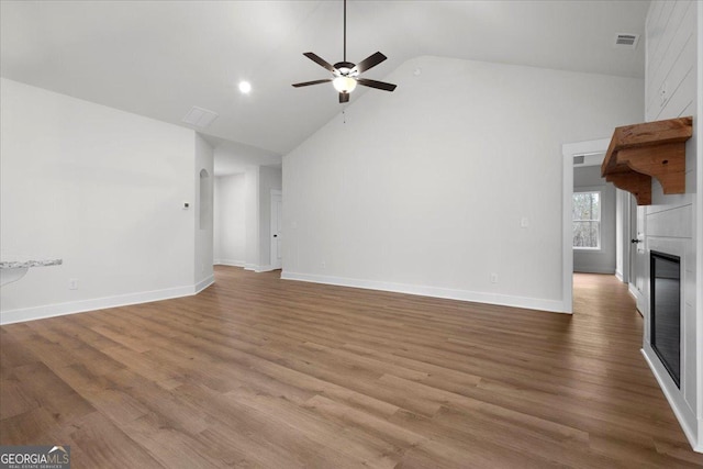 unfurnished living room with ceiling fan, high vaulted ceiling, a fireplace, and light hardwood / wood-style floors