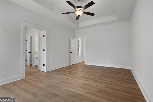 interior space with ceiling fan, a raised ceiling, and light hardwood / wood-style flooring