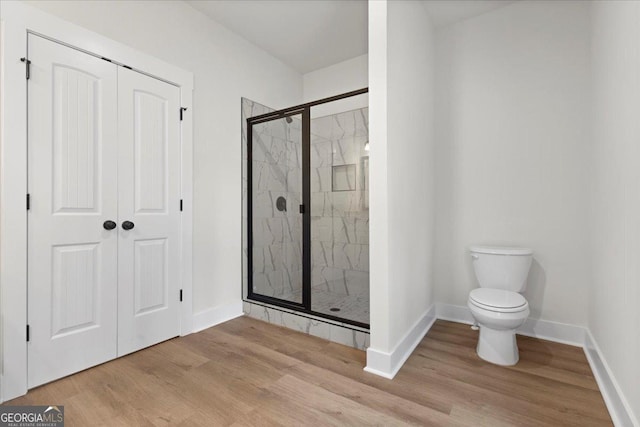 bathroom featuring hardwood / wood-style flooring, toilet, and a shower with door