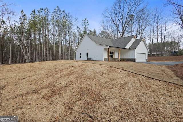 view of home's exterior with a garage, a lawn, and central AC