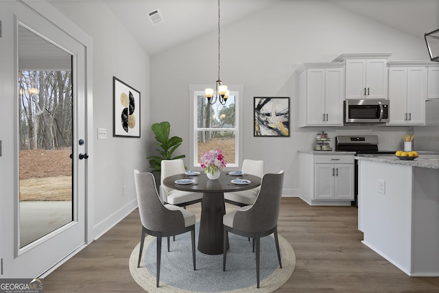 dining area featuring a healthy amount of sunlight, dark wood-type flooring, and a notable chandelier