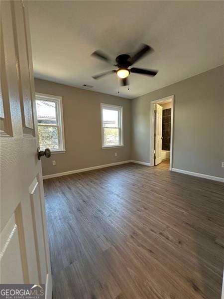 spare room featuring ceiling fan, a healthy amount of sunlight, and dark wood-type flooring