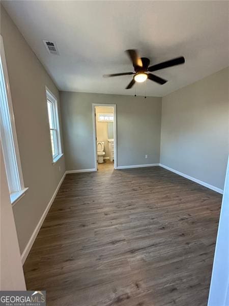 unfurnished bedroom with ceiling fan, connected bathroom, and dark wood-type flooring