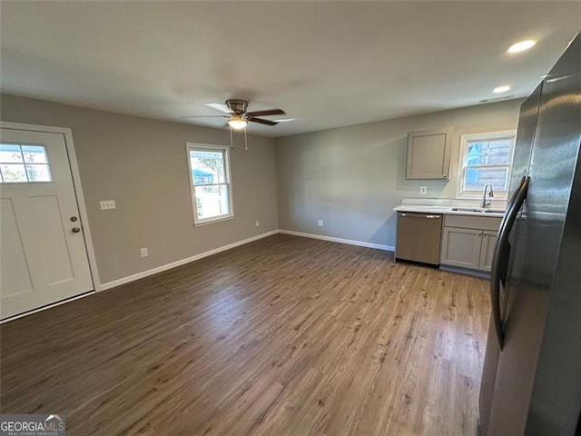 kitchen with dishwasher, sink, black fridge, light wood-type flooring, and gray cabinetry