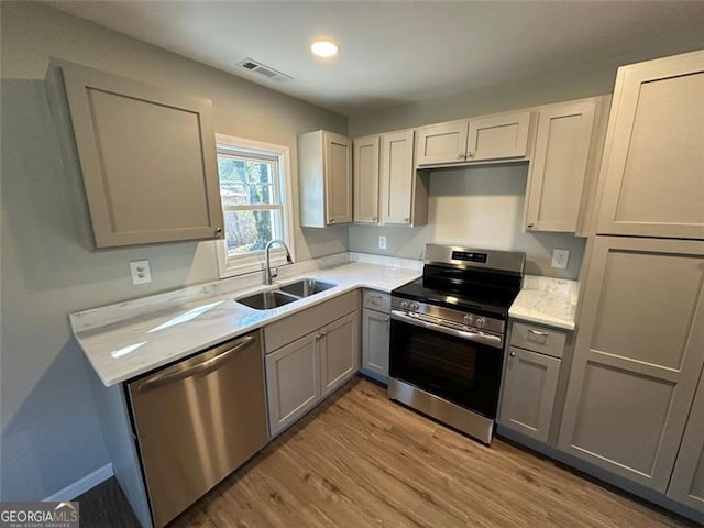 kitchen featuring sink, appliances with stainless steel finishes, gray cabinets, and light hardwood / wood-style flooring