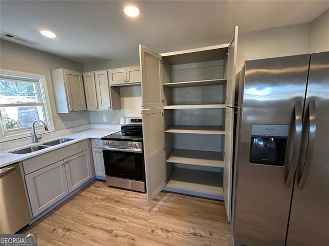 kitchen featuring sink, light wood-type flooring, gray cabinetry, and appliances with stainless steel finishes