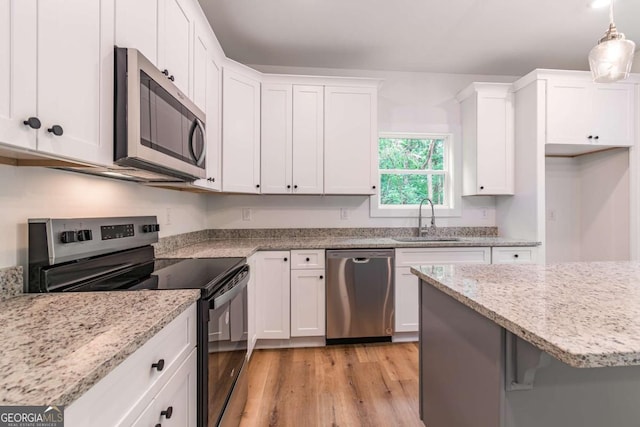 kitchen with sink, white cabinetry, hanging light fixtures, and stainless steel appliances