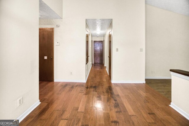 hallway with a textured ceiling and dark hardwood / wood-style floors