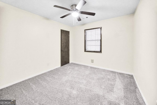 empty room featuring ceiling fan and carpet