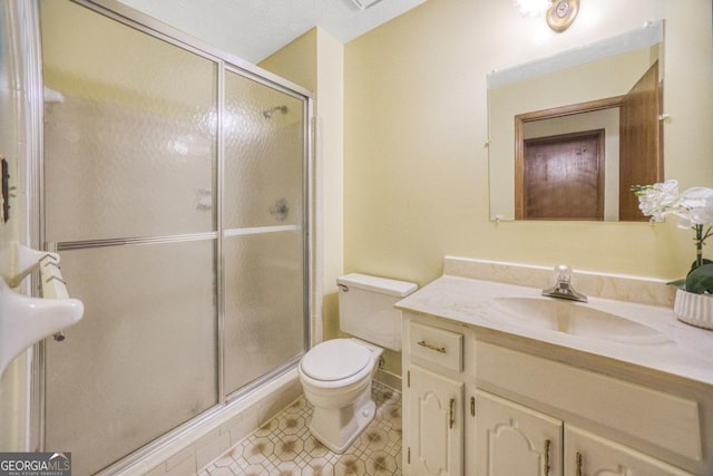 bathroom with a textured ceiling, a shower with door, toilet, and vanity