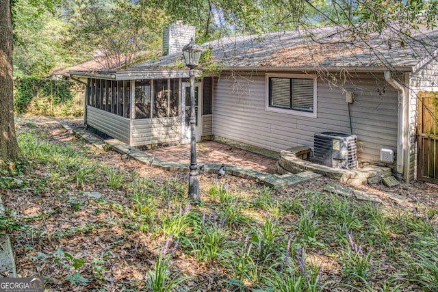 exterior space with a sunroom, a patio area, and cooling unit