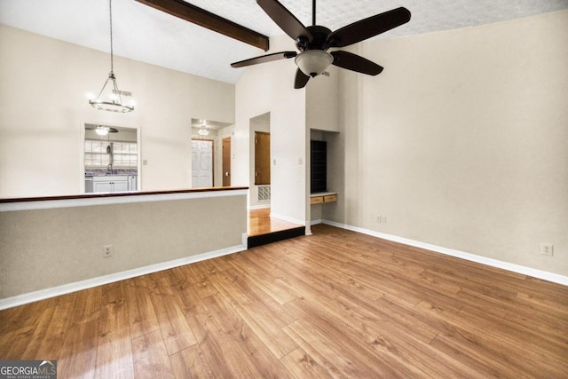 unfurnished living room featuring beam ceiling, a textured ceiling, ceiling fan with notable chandelier, high vaulted ceiling, and light hardwood / wood-style floors