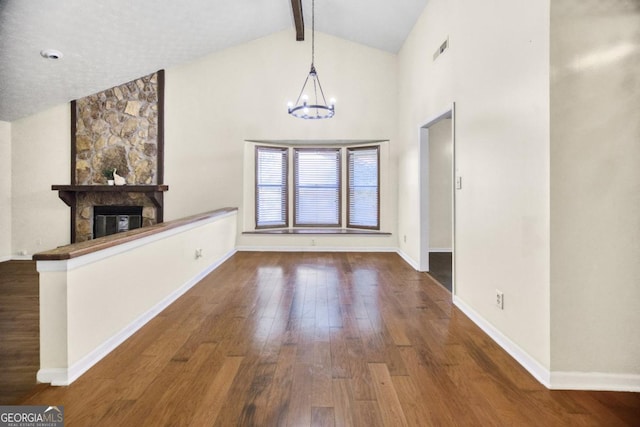 unfurnished living room featuring a fireplace, lofted ceiling with beams, dark hardwood / wood-style floors, and a notable chandelier
