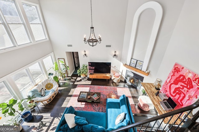 living room with dark hardwood / wood-style floors, a notable chandelier, and a towering ceiling