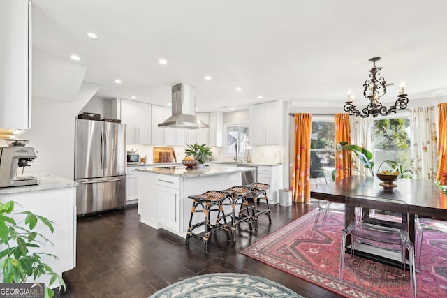 kitchen with appliances with stainless steel finishes, island exhaust hood, white cabinets, a kitchen island, and decorative light fixtures