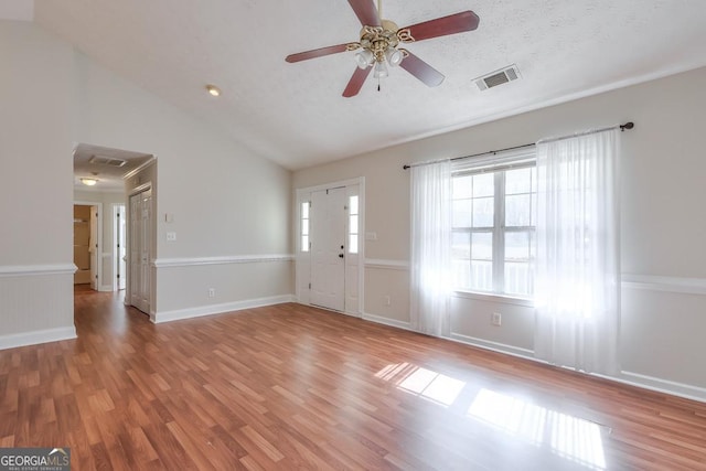 interior space with ceiling fan, wood-type flooring, vaulted ceiling, and a textured ceiling