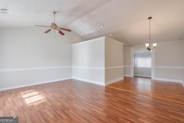 spare room with vaulted ceiling, ceiling fan with notable chandelier, and hardwood / wood-style floors