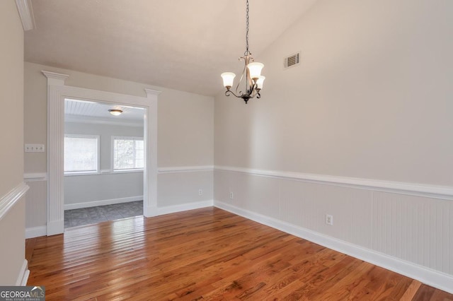 empty room featuring hardwood / wood-style flooring, vaulted ceiling, and a notable chandelier