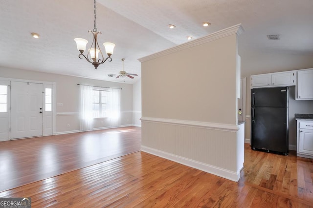 interior space featuring vaulted ceiling, ceiling fan with notable chandelier, and light wood-type flooring