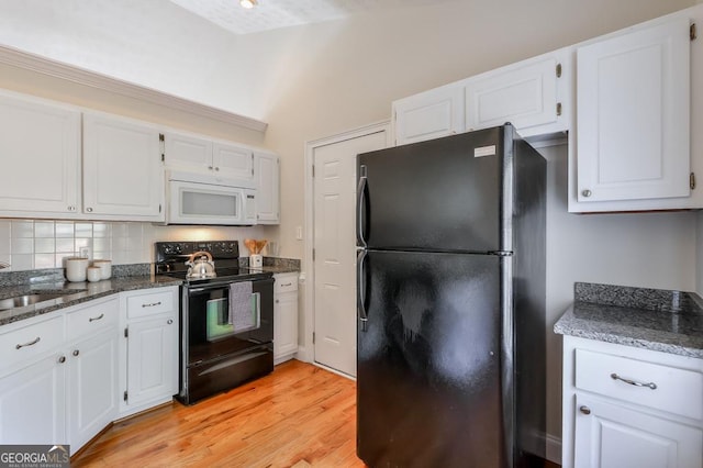 kitchen with sink, dark stone countertops, black appliances, light hardwood / wood-style floors, and white cabinets