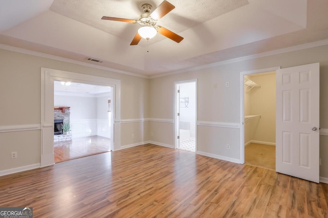 unfurnished room with a raised ceiling, a fireplace, and light wood-type flooring