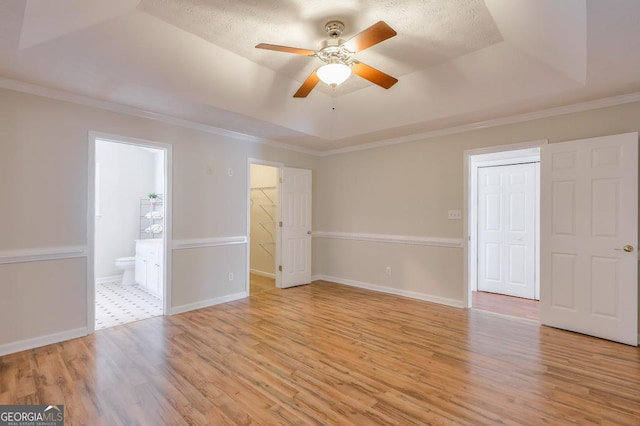 unfurnished room featuring crown molding, a tray ceiling, light hardwood / wood-style floors, and ceiling fan