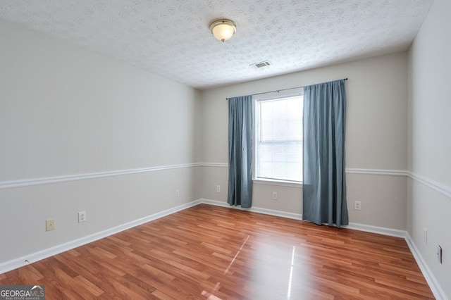 empty room with wood-type flooring and a textured ceiling