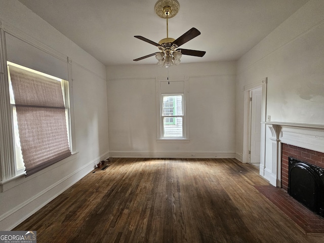 unfurnished living room featuring ceiling fan, a brick fireplace, and dark hardwood / wood-style flooring