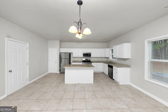 kitchen with light stone countertops, appliances with stainless steel finishes, white cabinetry, a kitchen island, and decorative light fixtures