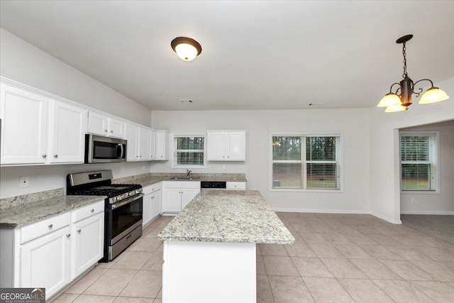 kitchen featuring light stone countertops, appliances with stainless steel finishes, a kitchen island, decorative light fixtures, and white cabinetry