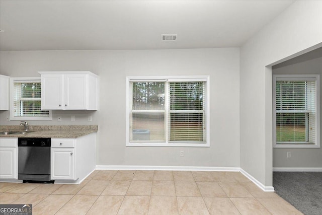 kitchen featuring white cabinetry, plenty of natural light, stainless steel dishwasher, and light tile patterned flooring